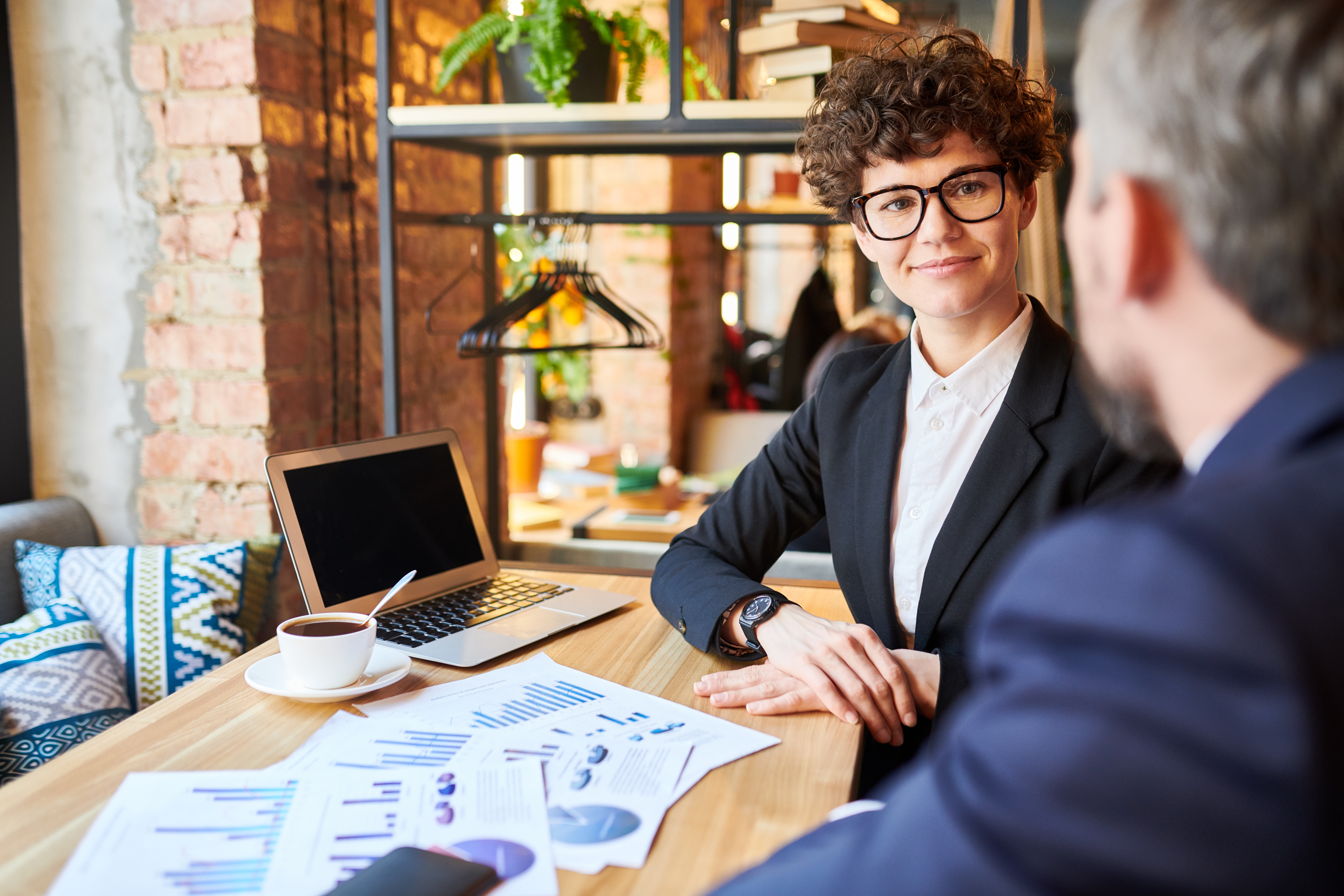 A business growth consultant reviewing performance charts during a strategy meeting with a client.