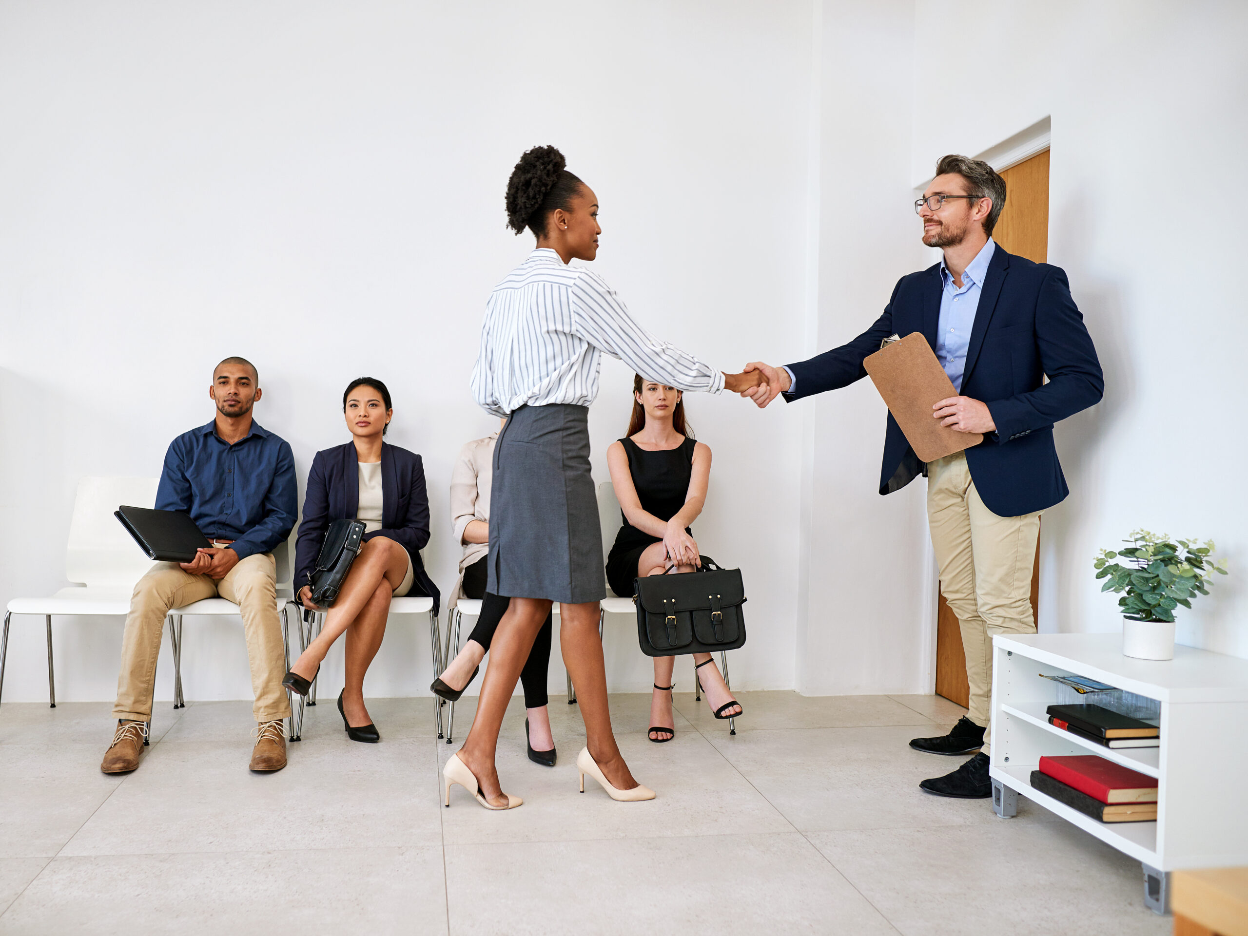 Confident new hire shaking hands with a recruiter after a successful job interview.